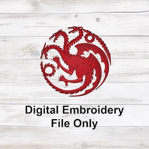May include: Red dragon emblem with three heads, wings, and a circular design. The text "Digital Embroidery File Only" is below the emblem. The design is on a white wooden background.