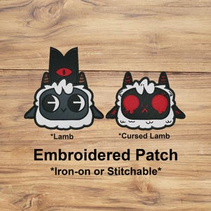 May include: Two embroidered patches: a cartoon lamb and a cursed lamb. The lamb has a black head with a red eye, the cursed lamb has red eyes. The text "Embroidered Patch" is below the patches. The patches are iron-on or stitchable.