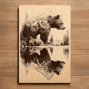 Puede incluir: Panel de madera con una ilustración detallada de un oso de pie cerca de un lago, con montañas y árboles en el fondo. El reflejo del oso es visible en el agua, creando un diseño simétrico. La obra de arte está en tonos marrones y beige.