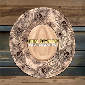 May include: A light brown cowboy hat design with a detailed peacock feather pattern around the brim. The hat features the text "DIGITAL DOWNLOAD READY TO ENGRAVE PNG". The hat is set against a wooden background.