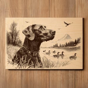 Pode incluir: Arte de parede em madeira com uma ilustração a preto e branco de um cão junto a um lago. O cão, com coleira, olha para a direita. Patos nadam no lago, com montanhas e árvores ao fundo. A obra está montada numa tábua de madeira.