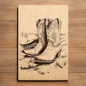 May include: A wood panel featuring a detailed illustration of cowboy boots, a hat, and rope. The boots are intricately designed with floral patterns. The artwork is in shades of brown and beige, evoking a rustic, Western theme.