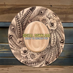 May include: A beige cowboy hat featuring a design of feathers, flowers, and the text "DIGITAL DOWNLOAD READY TO ENGRAVE PNG". The hat has a wide brim and a rounded crown, suitable for engraving.
