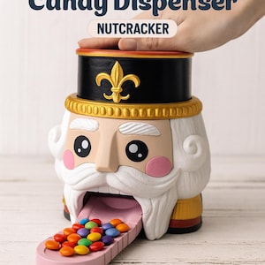 May include: A novelty candy dispenser shaped like a nutcracker. The dispenser has a black hat with a gold fleur-de-lis, a white beard, and pink cheeks. The dispenser is filled with colorful candies.
