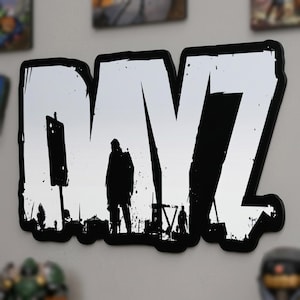 Può includere: Opera d'arte da parete in bianco e nero con le lettere "DMZ" e una silhouette di una persona e di edifici all'interno. L'opera d'arte ha uno stile grunge invecchiato con un bordo nero.