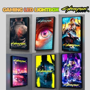 May include: A collection of six rectangular LED lightboxes featuring Cyberpunk 2077 artwork. The designs include a character in a jacket, a close-up of an eye, a motorcycle scene, a futuristic car, a yellow city silhouette, and a group of characters.