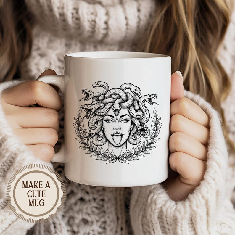 May include: White ceramic mug featuring a black and white illustration of Medusa with snakes for hair, a laurel wreath, and her tongue sticking out. The mug has a handle and the text "MAKE A CUTE MUG" on a sticker.