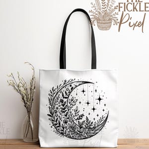 May include: A white tote bag with black handles features a black and white illustration of a crescent moon surrounded by floral designs and stars. The text "The Fickle Pixel" is printed in brown on the top right corner of the bag.