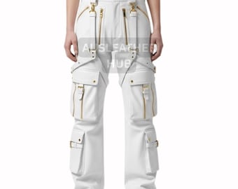 Könnte beinhalten: Weiße Lederhose mit mehreren Taschen, goldenen Reißverschlüssen und Hosenträgern. Die Hose hat ein gerades Bein-Design und verfügt über goldfarbene Beschläge an den Taschen und Hosenträgerbefestigungen. Der Text "ALSLEATHER HUB" ist sichtbar.