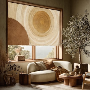 Può includere: Una tenda a rullo per finestra con una stampa astratta su larga scala di cerchi concentrici in tonalità marrone, beige e color cuoio. Il design imita l'aspetto degli anelli delle venature del legno, coprendo il telaio rettangolare.
