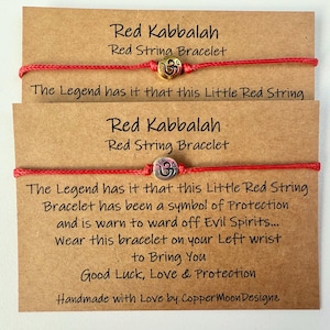 May include: Two red Kabbalah string bracelets with metallic charms, presented on brown cards. The cards contain text about the bracelet's symbolism. Handmade bracelets designed to bring good luck.