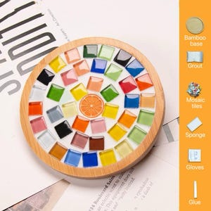 Pode incluir: Um porta-copos circular com base de bambu apresentando um design de mosaico com azulejos de vidro quadrados coloridos e um motivo central de fatia de laranja. O painel lateral exibe &iacute;cones e etiquetas para base de bambu, argamassa, azulejos, esponja, luvas e cola.