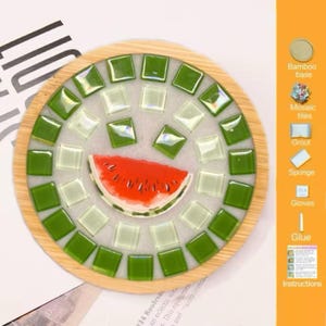 Pode incluir: Um porta-copos circular de bambu com um design de mosaico de azulejos de vidro quadrados em verde escuro e claro que rodeiam um gr&aacute;fico central de uma fatia de melancia, exibido ao lado de uma lista dos componentes do kit.