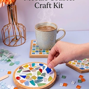 May include: A mosaic coaster craft kit featuring wooden coaster bases, assorted colourful glass tiles in red, blue, green, orange, and white, and a white adhesive surface. The kit includes a circular wooden base and a square wooden base.