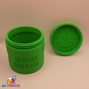May include: Bright green container with a matching lid. The container has the words "Jabbas Cabbage" embossed on the side. The lid has the words "Don't Panic, It's Organic" and a cannabis leaf.
