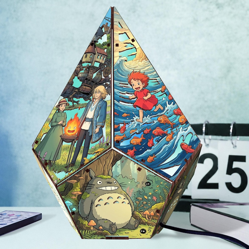 May include: A multi-faceted, diamond-shaped wooden lamp featuring colorful, detailed illustrations from animated films. The panels depict a large grey creature in a forest, a girl running through ocean waves with fish, and two figures near a fire.