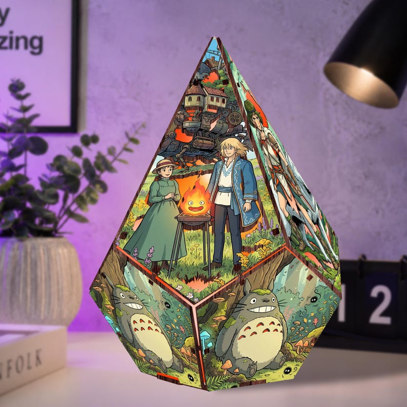 May include: A diamond-shaped wooden lamp featuring colorful anime illustrations. The front panel displays a girl in a green dress and a man in a blue coat standing by a fire, while the lower section depicts a large gray creature in a forest.