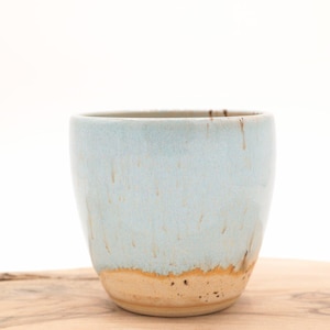 Può includere: Una tazza in ceramica blu chiaro con un bordo marrone e una base marrone chiaro. La tazza ha una glassa macchiata ed è fatta a mano.