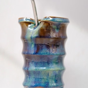 Peut inclure: Une calebasse à yerba maté en céramique faite à la main avec une paille en acier inoxydable. La calebasse présente un design nervuré avec un mélange d'émail bleu, marron et vert. La calebasse mesure environ 13 cm de haut.