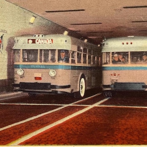 May include: A vintage postcard showing two buses traveling through a tunnel. The tunnel is decorated with flags representing the United States and Canada. The text on the postcard reads "TUNNEL BETWEEN DETROIT, U.S. AND WINDSOR, ONT. SHOWING BUSSES."