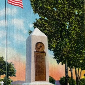May include: Vintage postcard featuring the Barbara Fritchie Monument in Frederick, Maryland. The monument is a white obelisk with a bronze plaque, set against a backdrop of green trees and a blue sky. An American flag waves in the breeze.