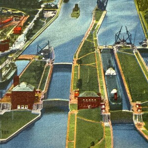 May include: Vintage postcard featuring an aerial view of the Four Famous Soo Locks in Sault Ste. Marie, Michigan. The image shows the locks, waterways, buildings, and bridges. The postcard has a cream-colored border and the text "Aerial View of the Four Famous Soo Locks, Sault Ste. Marie, Mich."