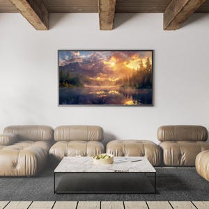 May include: A framed landscape art print depicting a mountain lake scene at sunrise. The artwork features a vibrant sky with orange and yellow hues, reflecting in the calm water. The room includes a leather sofa, a marble coffee table, and a gray rug.