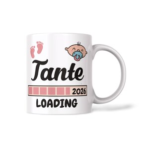 Op de afbeelding: Witte keramische mok met het woord "Tante" in zwart schrift, een baby-afbeelding en roze babyvoetjes. De mok heeft ook de tekst "LOADING" en het jaar "2026" in een roze laadbalkontwerp.
