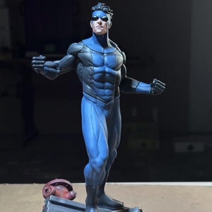 Könnte beinhalten: Eine detaillierte Superhelden-Figur in einem strukturierten blau-dunkelgrauen Anzug mit einer Augenmaske. Die Figur steht in einer dynamischen Pose auf einem Sockel mit Trümmern und einem roten Hydranten und zeigt eine ausgeprägte Muskulatur.