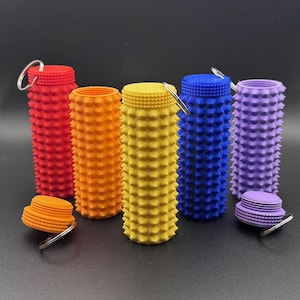 Op de afbeelding: Een verzameling kleurrijke flesstoppers in rood, oranje, geel, blauw en paars. Elke stopper heeft een ring voor gemakkelijk hanteren. De stoppers zijn cilindrisch met een stekelig oppervlakteontwerp.
