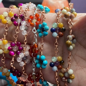 May include: A collection of beaded bracelets in various colors, including yellow, pink, white, red, and turquoise. The beads are clustered together and connected by copper and silver wire. The bracelets are displayed close together.