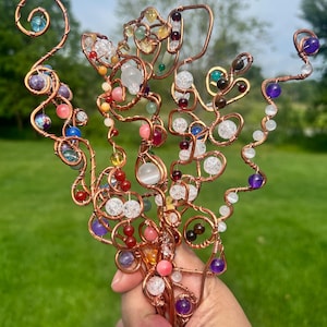 May include: A decorative sculpture crafted from twisted copper wire shaped into multiple branching stems. The wire structure is adorned with a variety of colorful, round gemstone beads in shades of purple, blue, red, yellow, and clear white.