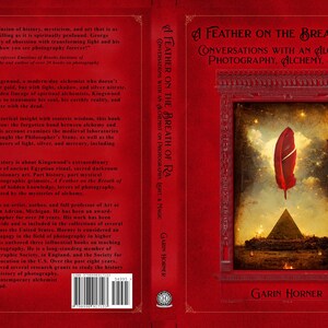 May include: Book cover for "A Feather on the Breath of Ra: Conversations with an Alchemist on Photography, Alchemy, & Magic." The red cover features a central image of a red feather floating above a pyramid.