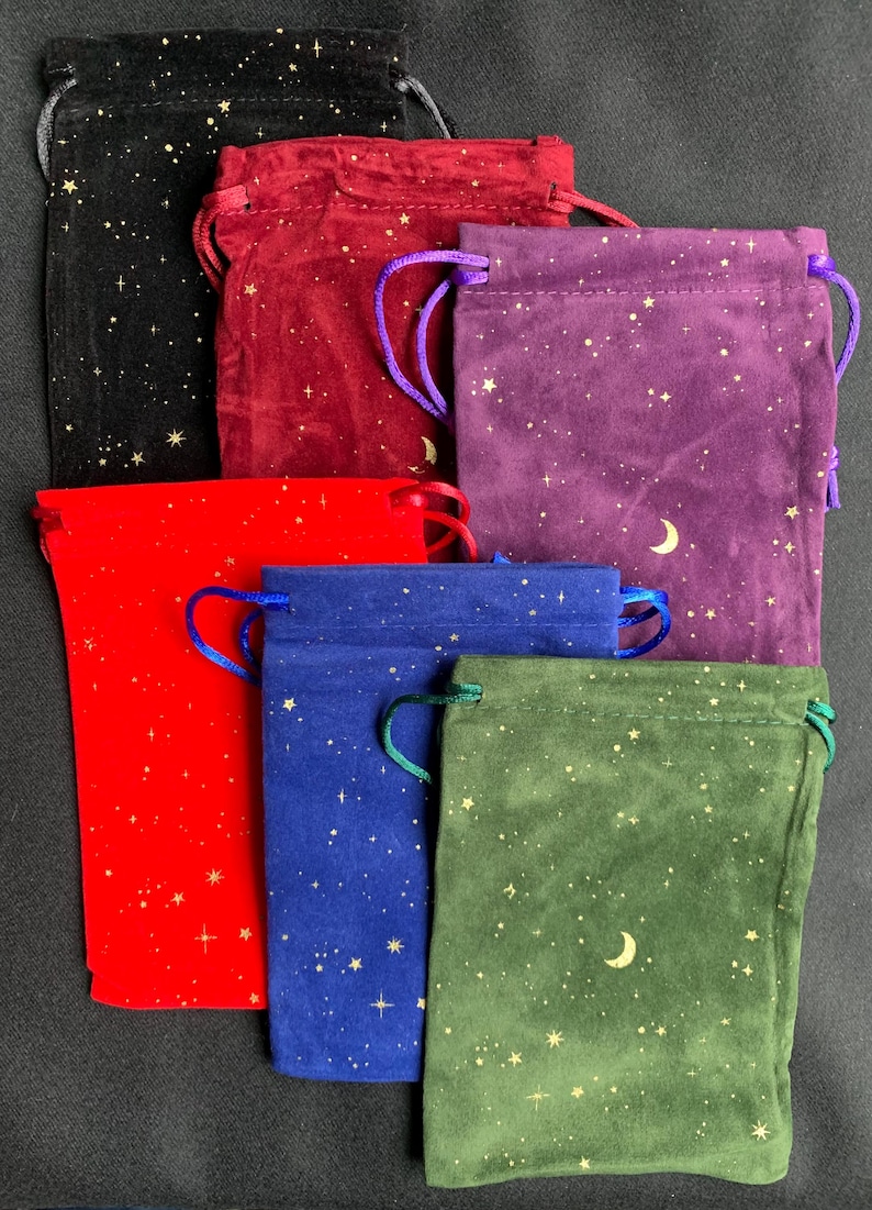 May include: Six velvet drawstring pouches with gold star and crescent moon patterns. The pouches are in black, burgundy, purple, red, blue, and green.