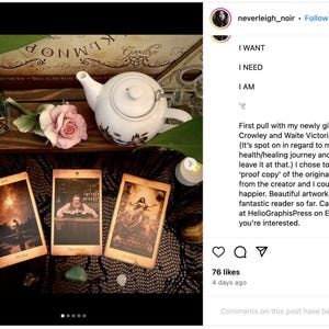 May include: Three tarot cards with dark, detailed illustrations are laid out on a black lace tablecloth. The cards are surrounded by a teacup, a candle, and a rose. The text on the cards reads "The Star", "The Hanged Man", and "The Empress". The caption reads "First pull with my newly gifted Crowley and Waite Victorian Tarot. (It's spot on in regard to my personal health/healing journey and I'll just leave it at that.) I chose to get a 'proof copy' of the original deck from the creator and I couldn't be happier. Beautiful artwork and a fantastic reader so far. Can be found at HelioGraphisPress on Etsy if you're interested."