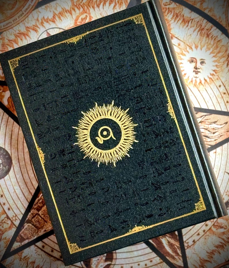 K&ouml;nnte beinhalten: Ein dunkelgr&uuml;nes Buch mit goldenen Akzenten und einem Sonnenstrahl-Design. Das Cover zeigt ein goldenes Sonnenstrahl-Emblem mit einem Auge in der Mitte und goldfarbenen Zierleisten. Das Buch befindet sich vor einem Hintergrund mit Himmelsbildern.