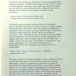 K&ouml;nnte beinhalten: Eine Buchseite mit dem Titel "A Feather on the Breath of Ra", die die Erforschung von Alchemie und Fotografie lobt. Der Text enth&auml;lt Zitate von Vincent Martin und Rebecca Zeiss sowie Details &uuml;ber den Inhalt des Buches. Gedruckt auf cremefarbenem Papier.