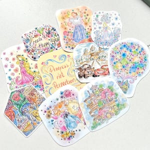 May include: A selection of vibrant, hand-drawn stickers with diverse illustrations. Designs include a princess, Winnie the Pooh characters, a house, cars, and floral arrangements. Some stickers have text that reads "Create a Happy Life" and "Progress not Perfection".