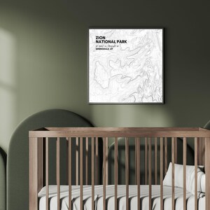 Może przedstawiać: Biały wydruk w ramie z czarno-białą mapą topograficzną Parku Narodowego Zion w Utah. Wydruk wisi na zielonej ścianie nad drewnianym łóżeczkiem z białym materacem i białą poduszką.
