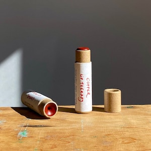 K&ouml;nnte beinhalten: Zwei braune Pappr&ouml;hrchen mit rotem Lippenbalsam. Das R&ouml;hrchen links ist mit "Pink" beschriftet und das R&ouml;hrchen rechts mit "Copper Lip Therapy".