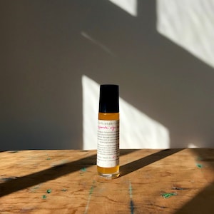 May include: A small amber glass bottle with a black roller top. The bottle is labeled "pomegranate eye serum" and contains organic botanical extracts, antioxidants, and phytochemicals to help reduce the appearance of dark circles, puffiness, and fine lines.