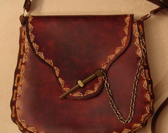 Peut inclure: Un sac bandoulière en cuir bordeaux avec fermeture à rabat et chaîne décorative. Le sac présente une longue bandoulière réglable et des détails cousus ornés sur les bords. Un fermoir en métal sécurise le rabat. Le sac mesure environ 20 cm de large.