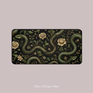 May include: A rectangular desk mat featuring a dark black background with a repeating pattern of winding green snakes and cream-coloured floral blossoms. The design includes intricate foliage and leaves intertwined with the snake bodies.