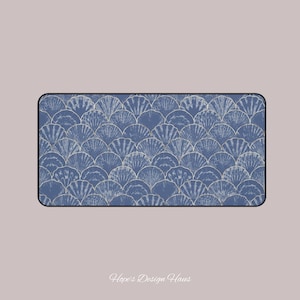 May include: Rectangular desk mat featuring a blue and white seashell pattern. The design is a repeating fan-like motif with a textured appearance. The mat has a black border and the text "Hope's Design Haus" is at the bottom.
