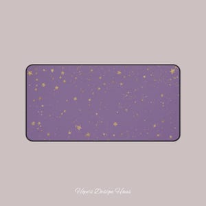 May include: A rectangular desk mat with a lavender background and scattered gold stars. The mat has a black border and the text "Hope's Design Haus" in the bottom center. The design is simple and elegant.