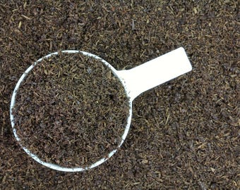 May include: A white plastic scoop filled with dark brown compost. The compost is made of shredded organic matter.