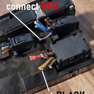 May include: A black plastic electrical component housing with exposed multi-colored wires. White lines point to specific wires with text labels that read connect RED and connect BLACK, indicating wiring instructions for the electrical assembly.