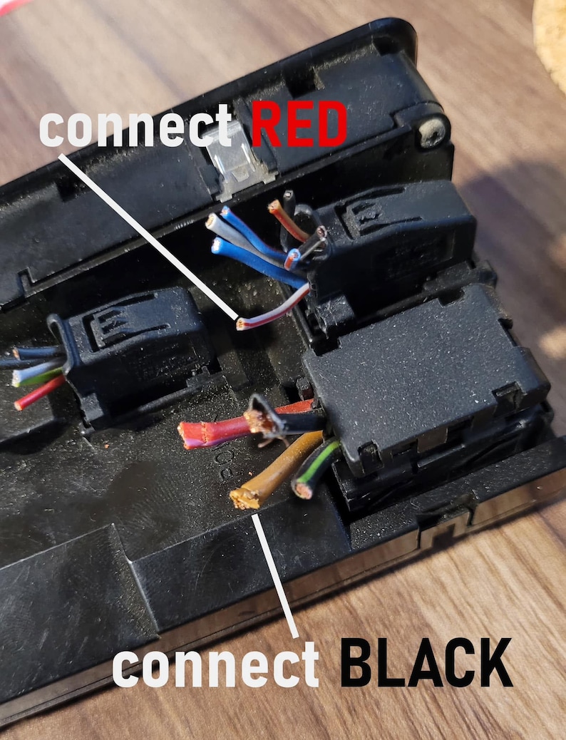 May include: A black plastic electrical component housing with exposed multi-colored wires. White lines point to specific wires with text labels that read connect RED and connect BLACK, indicating wiring instructions for the electrical assembly.