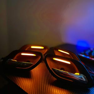 May include: A set of four black automotive interior door handle assemblies featuring integrated amber LED light strips and polished chrome levers. Each unit has a contoured housing with a horizontal light bar positioned above the handle.