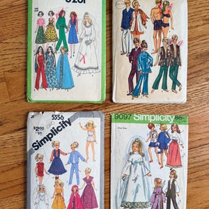 May include: Four vintage Simplicity sewing pattern envelopes labeled 8281, 9054, 5356, and 9097. Each rectangular paper envelope features colorful illustrations of various clothing styles, including dresses, capes, and suits, with printed text and model numbers.